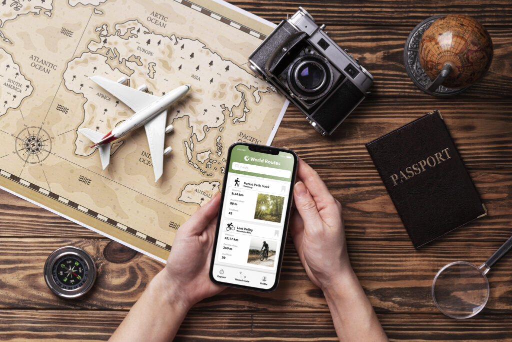 person holding phone and different tech with passport for travel